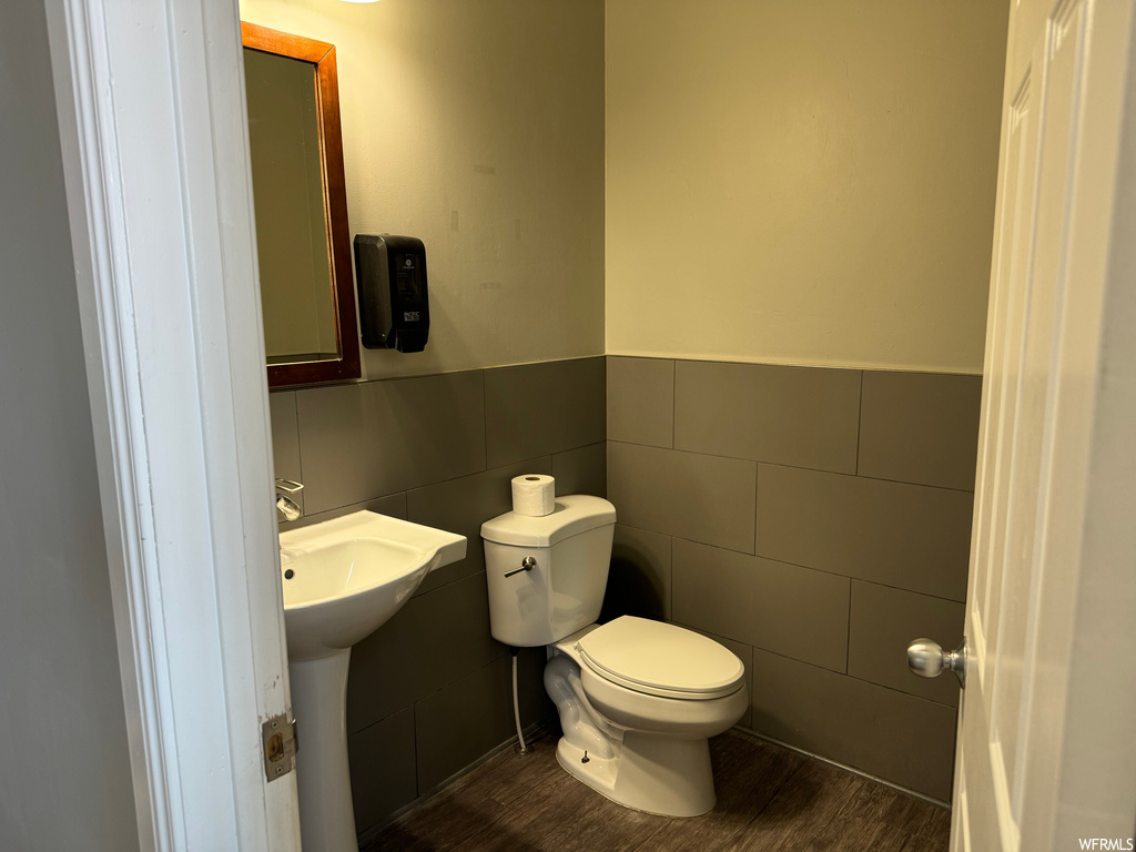 Bathroom with toilet, tile walls, sink, and hardwood / wood-style floors