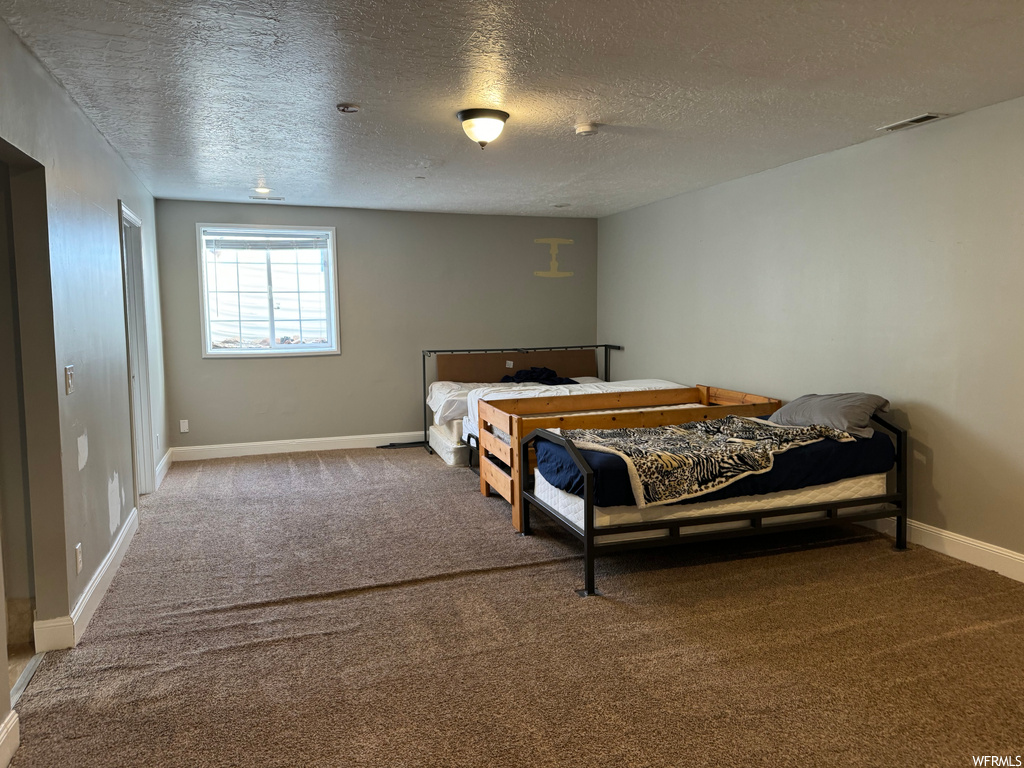 Bedroom with a textured ceiling and carpet floors