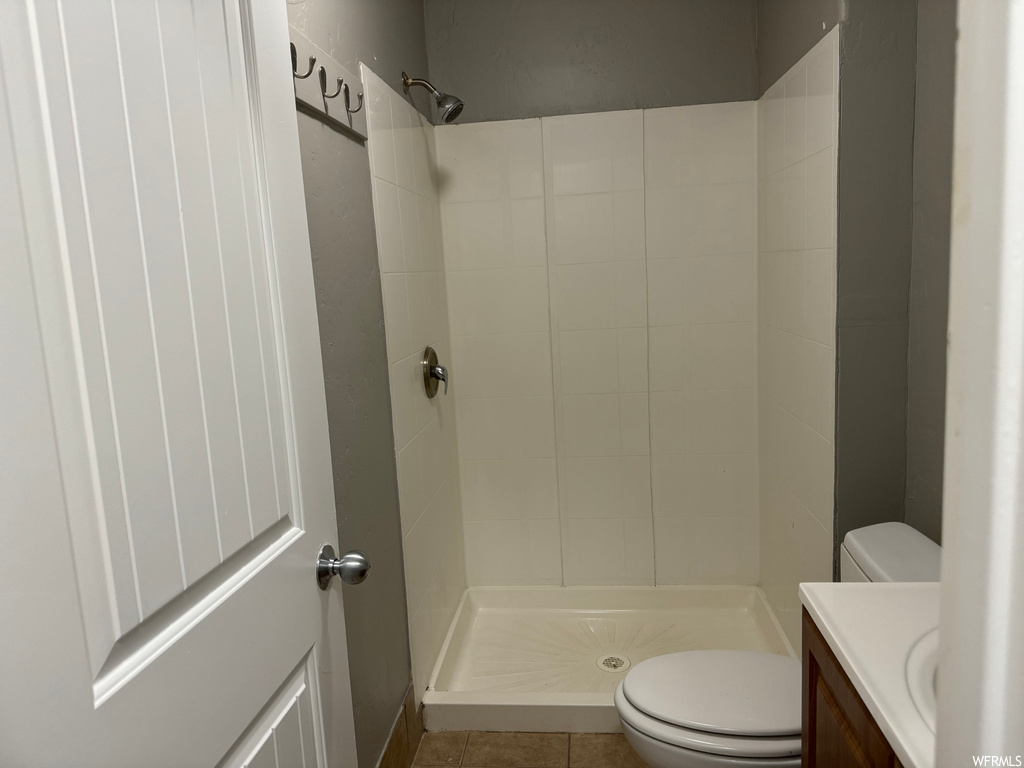 Bathroom featuring vanity, toilet, tile floors, and tiled shower