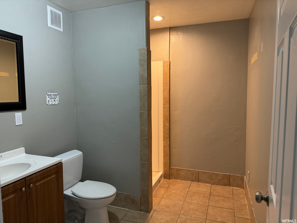 Bathroom with toilet, tile flooring, large vanity, and walk in shower