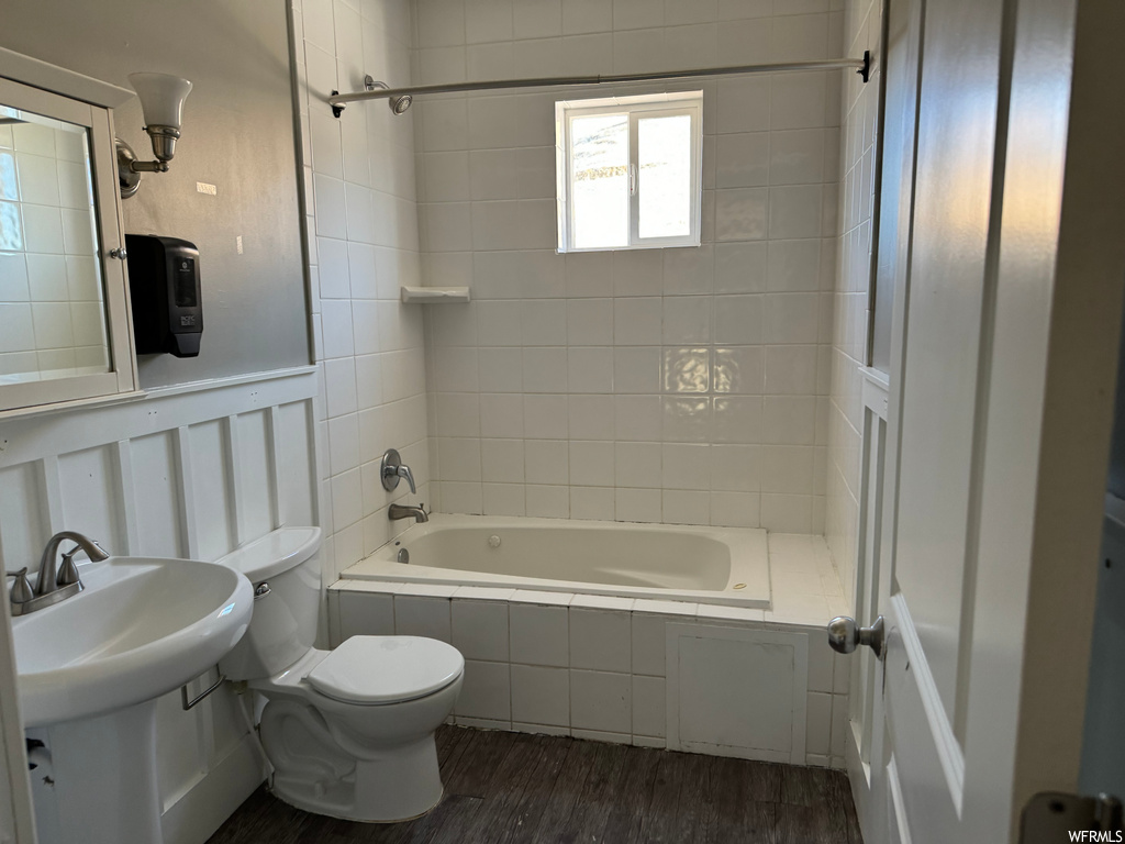 Full bathroom featuring toilet, tiled shower / bath combo, sink, and hardwood / wood-style flooring