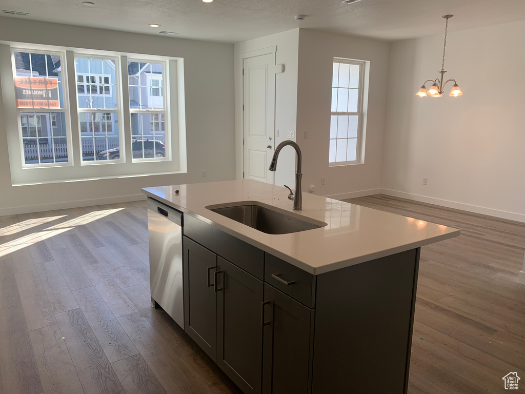 Kitchen featuring dark hardwood / wood-style flooring, dishwasher, a notable chandelier, sink, and a center island with sink