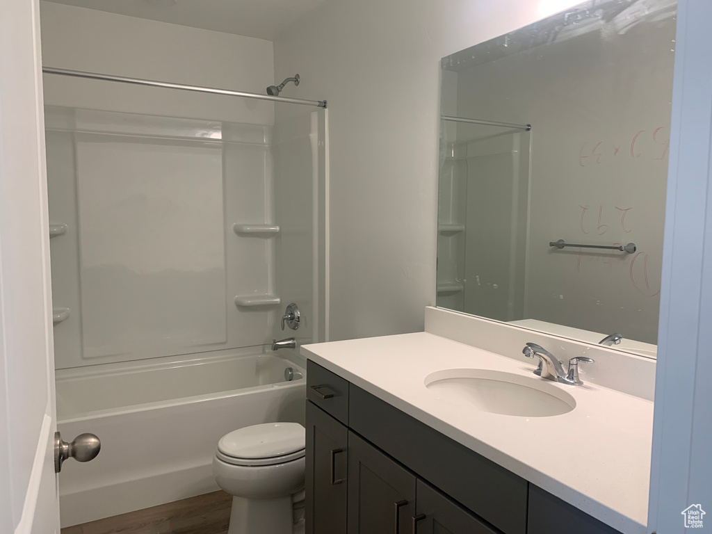 Full bathroom with shower / bathing tub combination, wood-type flooring, toilet, and vanity with extensive cabinet space