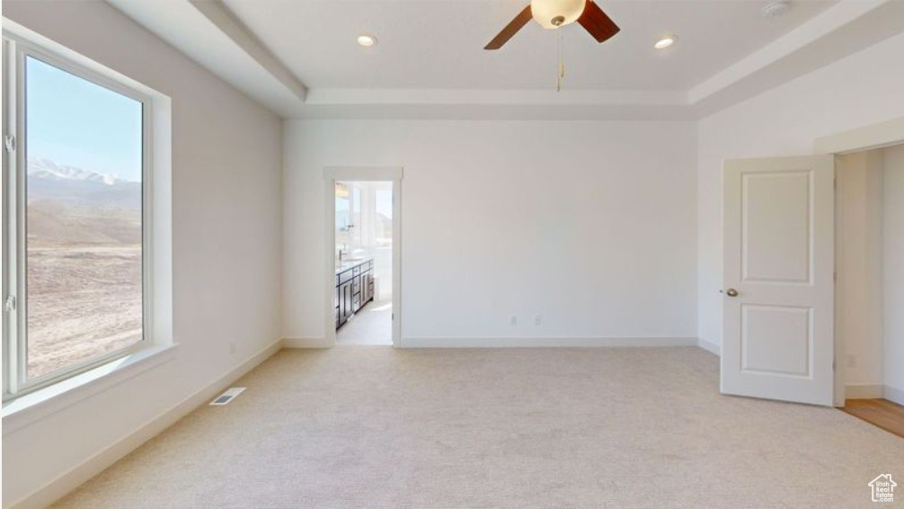 Unfurnished room with a tray ceiling, ceiling fan, and light carpet