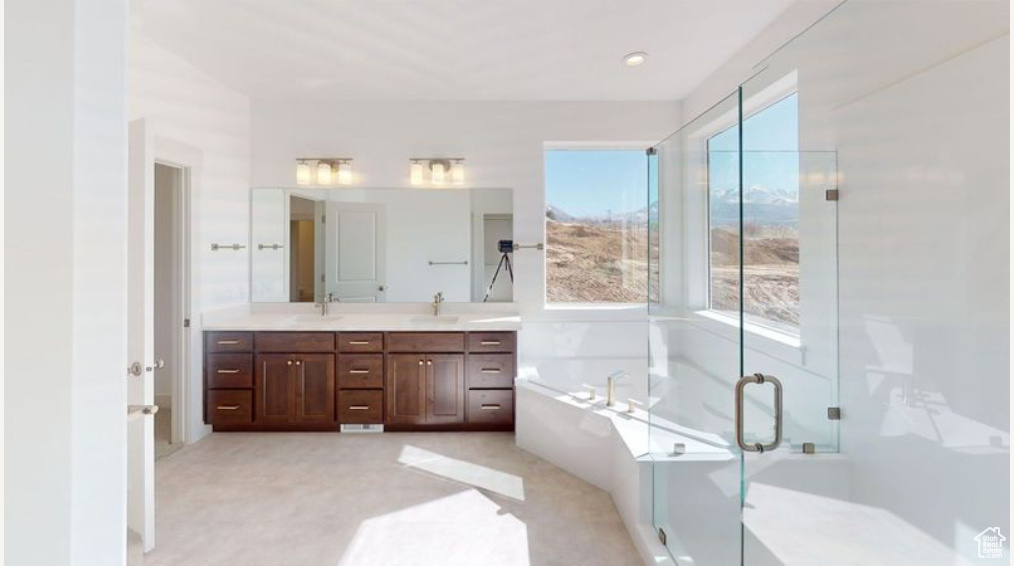 Bathroom with independent shower and bath, plenty of natural light, and vanity