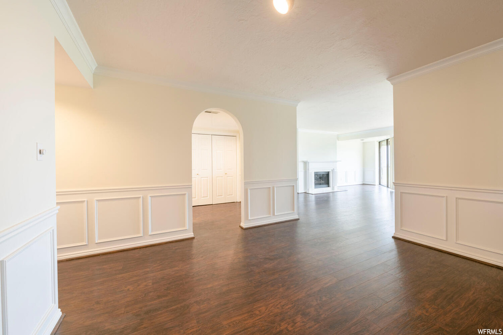 Empty room with ornamental molding and dark hardwood / wood-style floors