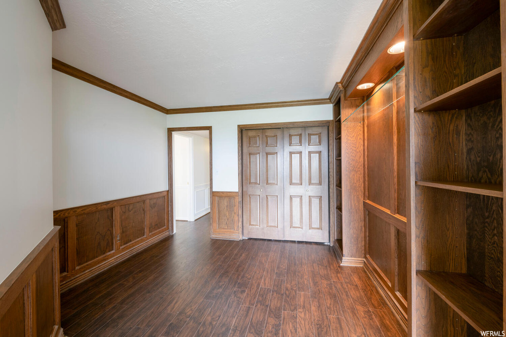 Empty room with dark wood-type flooring and ornamental molding
