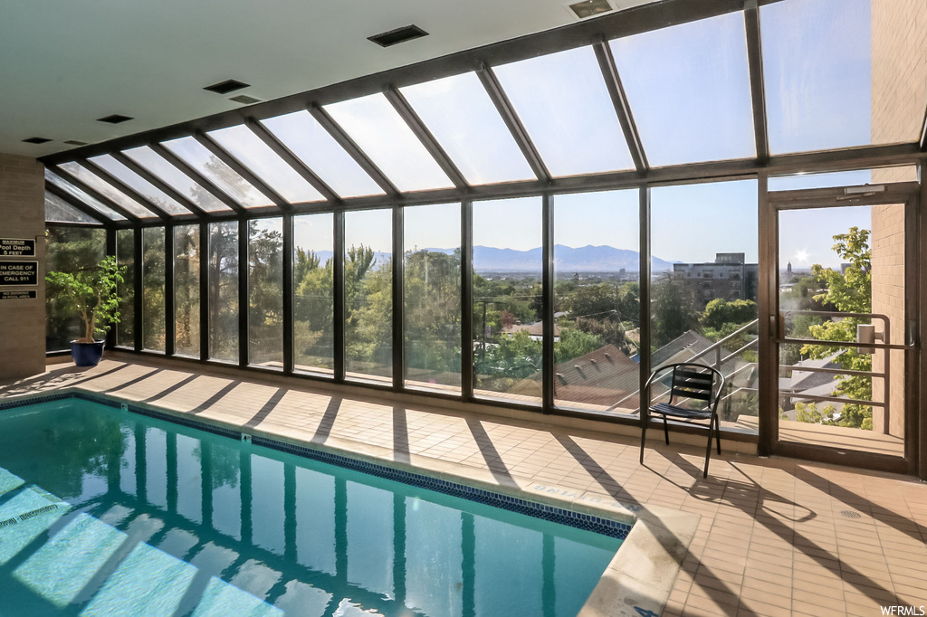 View of swimming pool featuring a patio, glass enclosure, and a mountain view