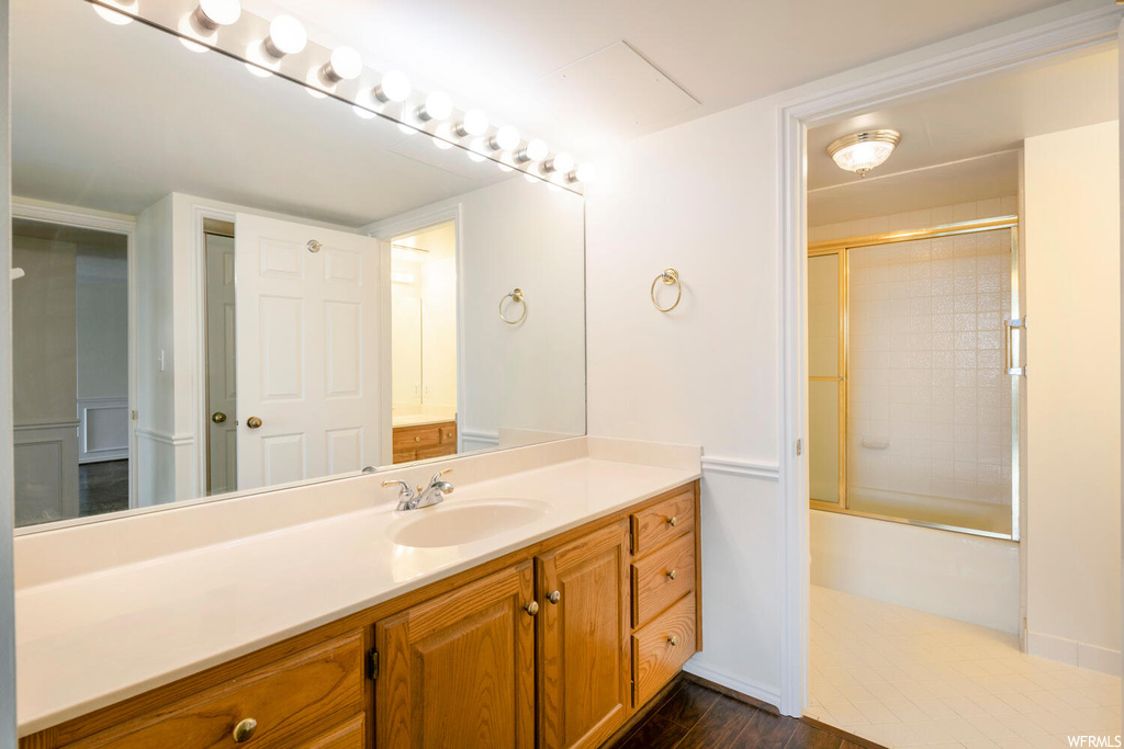 Bathroom featuring bath / shower combo with glass door, vanity, and wood-type flooring