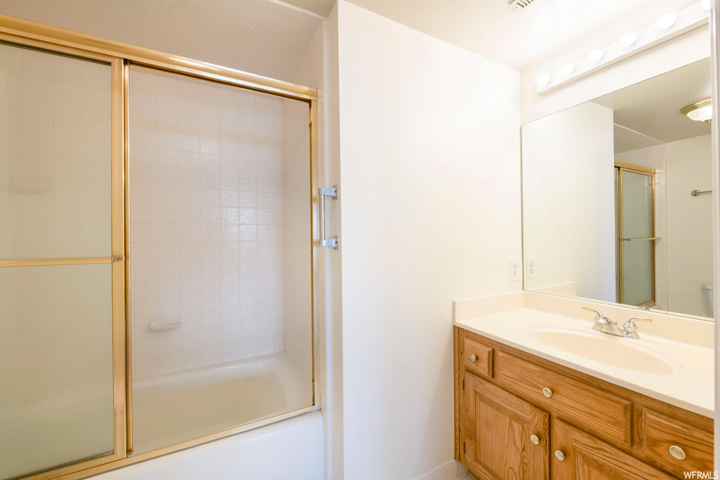 Bathroom with vanity and combined bath / shower with glass door