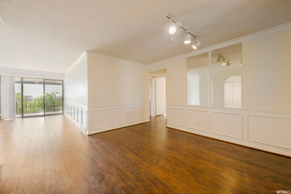 Unfurnished room featuring hardwood / wood-style floors, crown molding, and rail lighting
