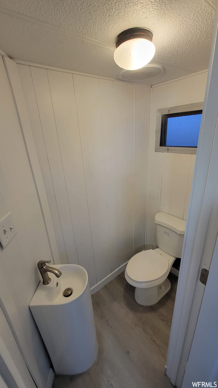 Bathroom featuring toilet, a textured ceiling, and wood-type flooring