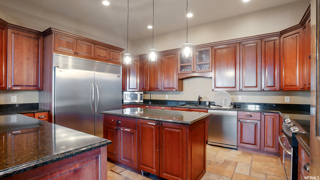 Kitchen with sink, appliances with stainless steel finishes, a center island, decorative light fixtures, and light tile floors