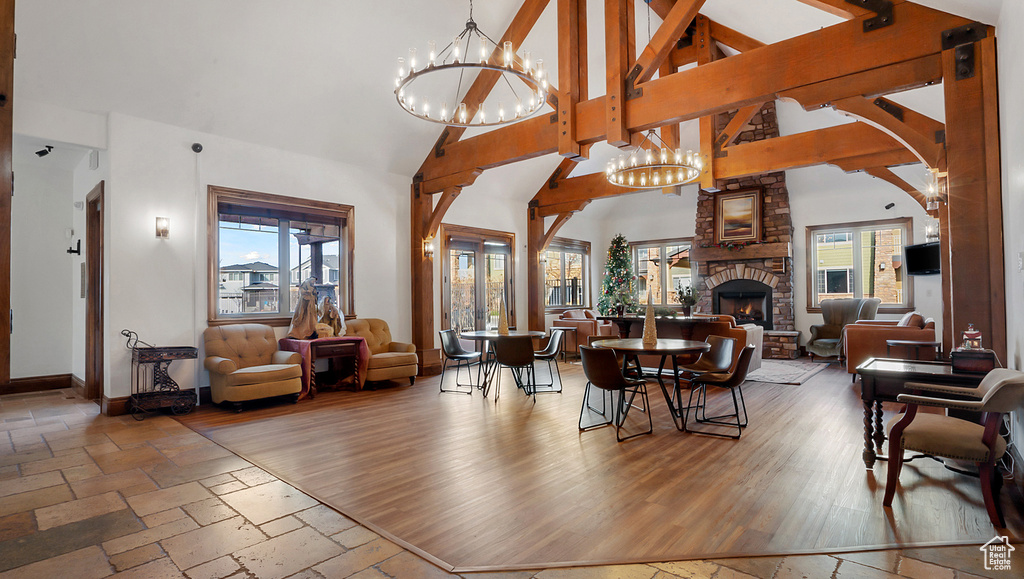Living room with hardwood / wood-style floors, high vaulted ceiling, a notable chandelier, and a stone fireplace