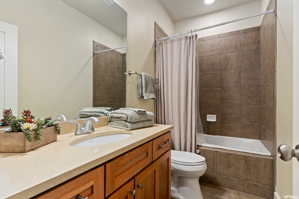 Full bathroom featuring toilet, shower / bath combo with shower curtain, tile flooring, and large vanity