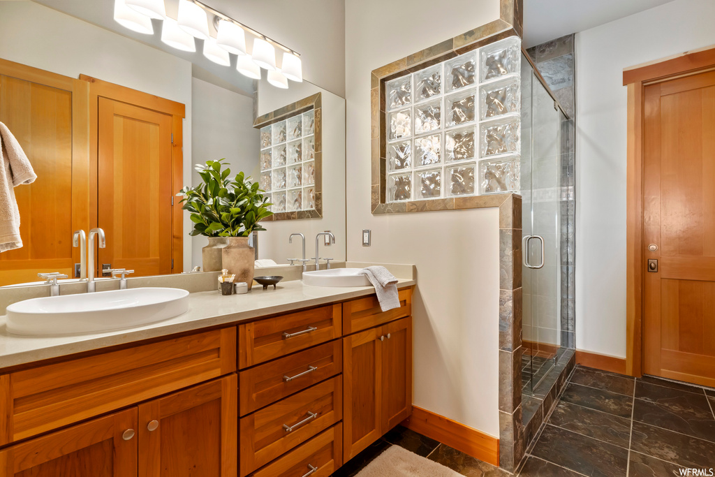 Bathroom featuring double sink, a shower with shower door, oversized vanity, and tile flooring