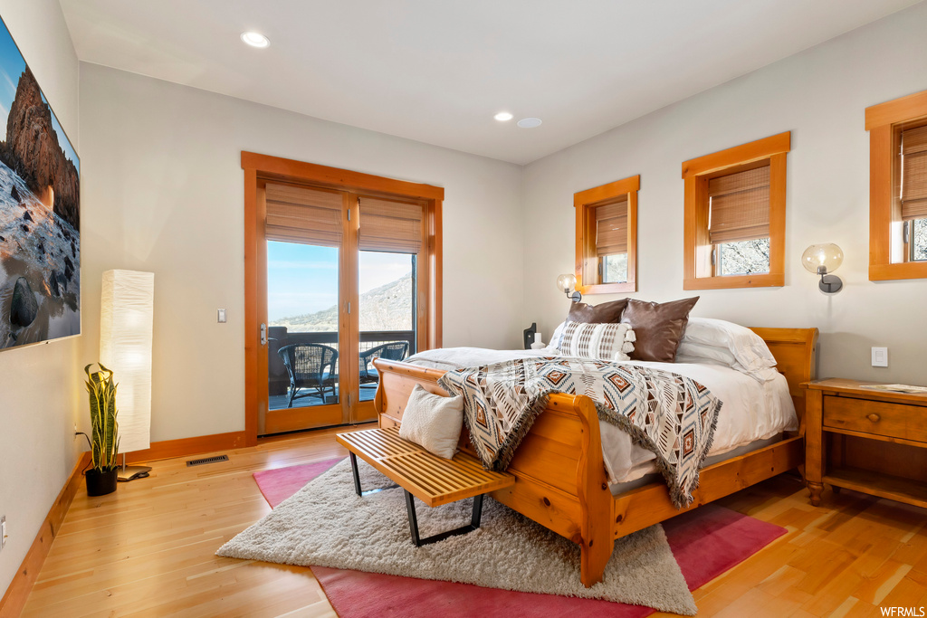 Bedroom with access to exterior, multiple windows, and light hardwood / wood-style floors