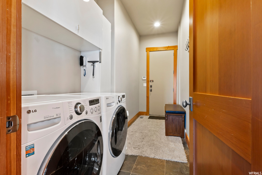 Laundry room with dark tile flooring and washing machine and dryer