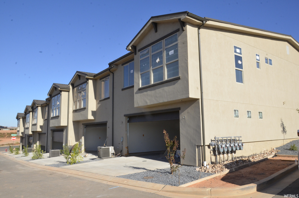 View of building exterior with a garage and central AC