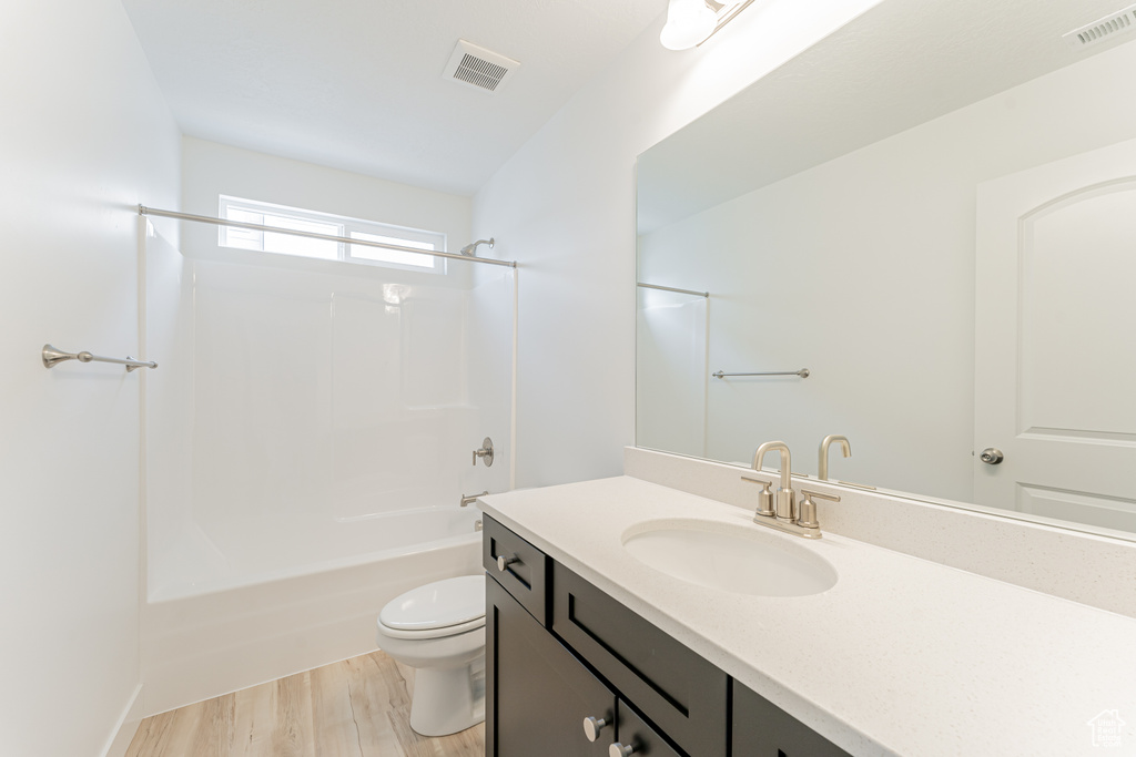 Full bathroom featuring wood-type flooring, oversized vanity, bathing tub / shower combination, and toilet