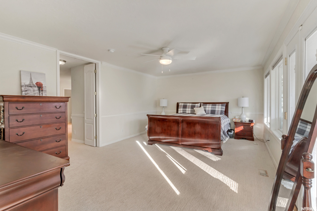 Bedroom with multiple windows, light carpet, ceiling fan, and ornamental molding