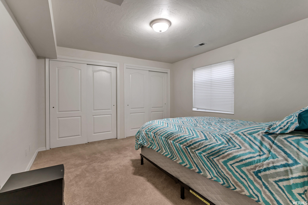 Bedroom featuring two closets and light carpet