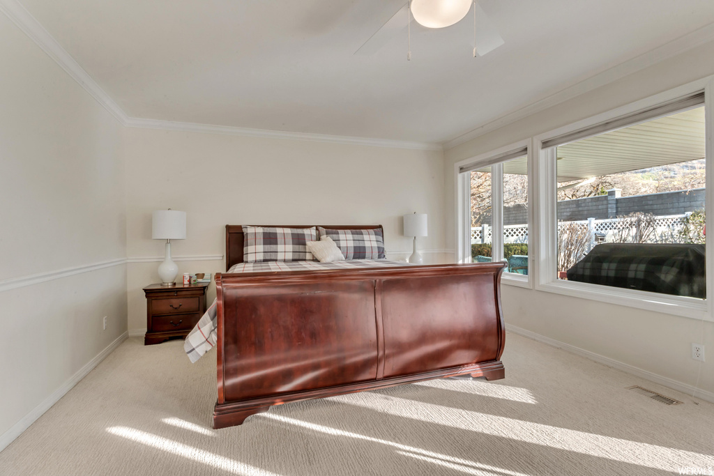 Bedroom featuring light carpet, ceiling fan, and crown molding