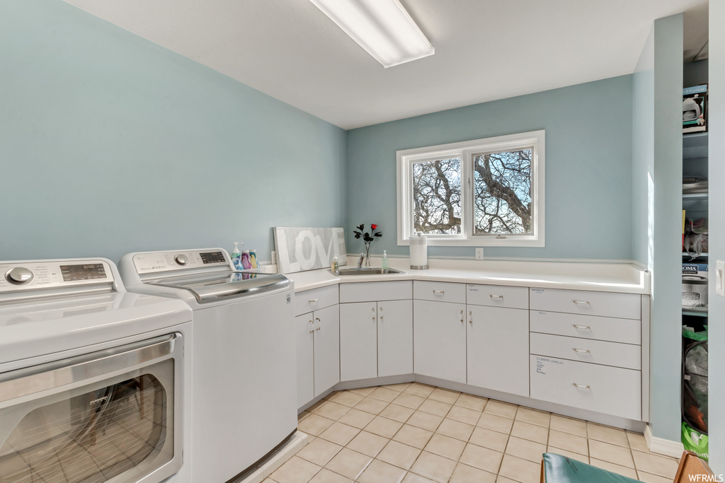 Laundry area featuring washer and dryer, cabinets, sink, and light tile floors