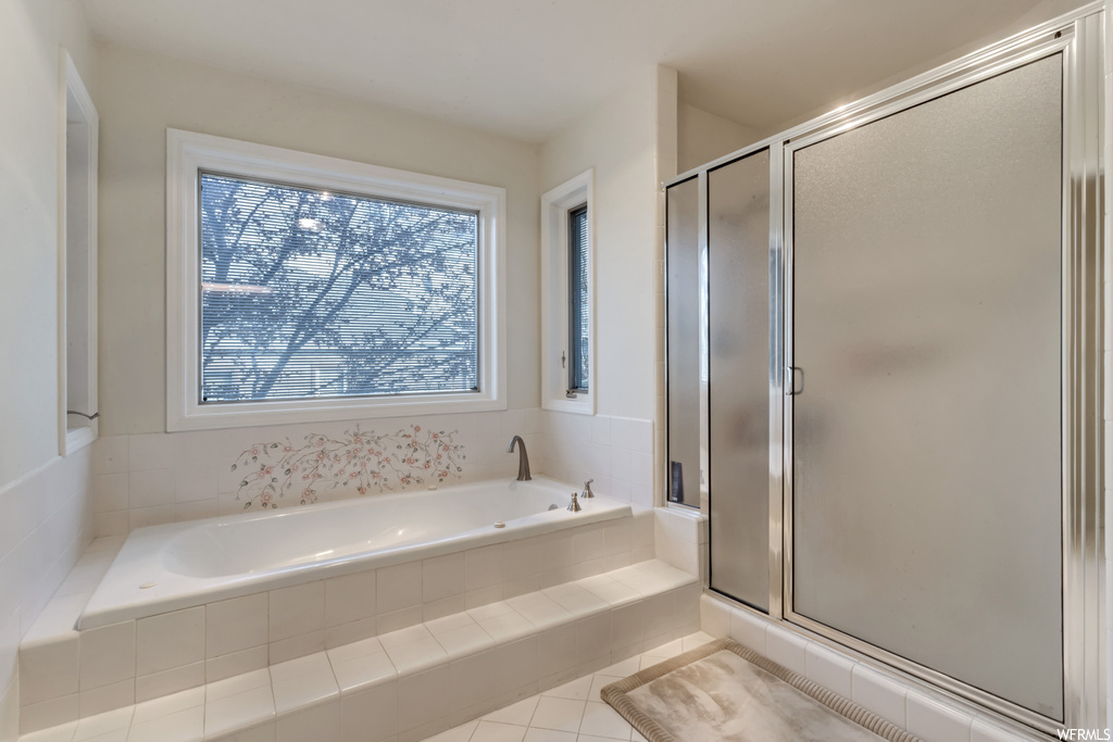 Bathroom with independent shower and bath, a wealth of natural light, and tile floors