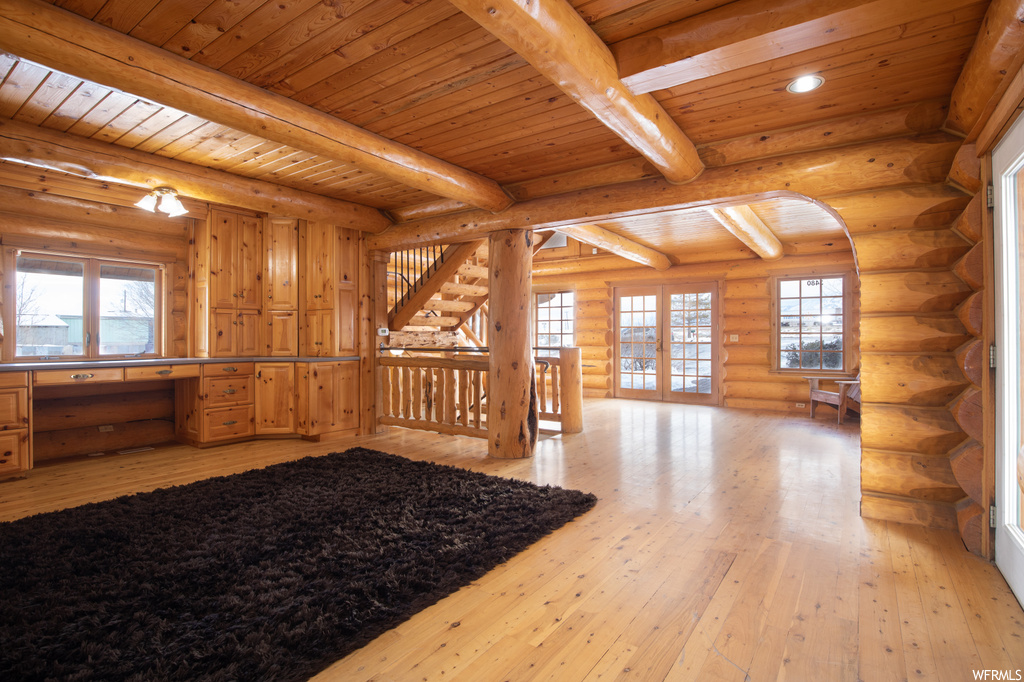 Interior space with light hardwood / wood-style flooring, wood ceiling, rustic walls, and beam ceiling