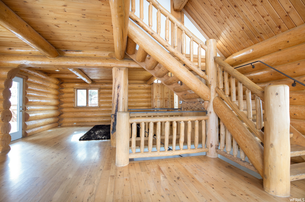 Bonus room featuring wood ceiling, light hardwood / wood-style floors, high vaulted ceiling, log walls, and beamed ceiling