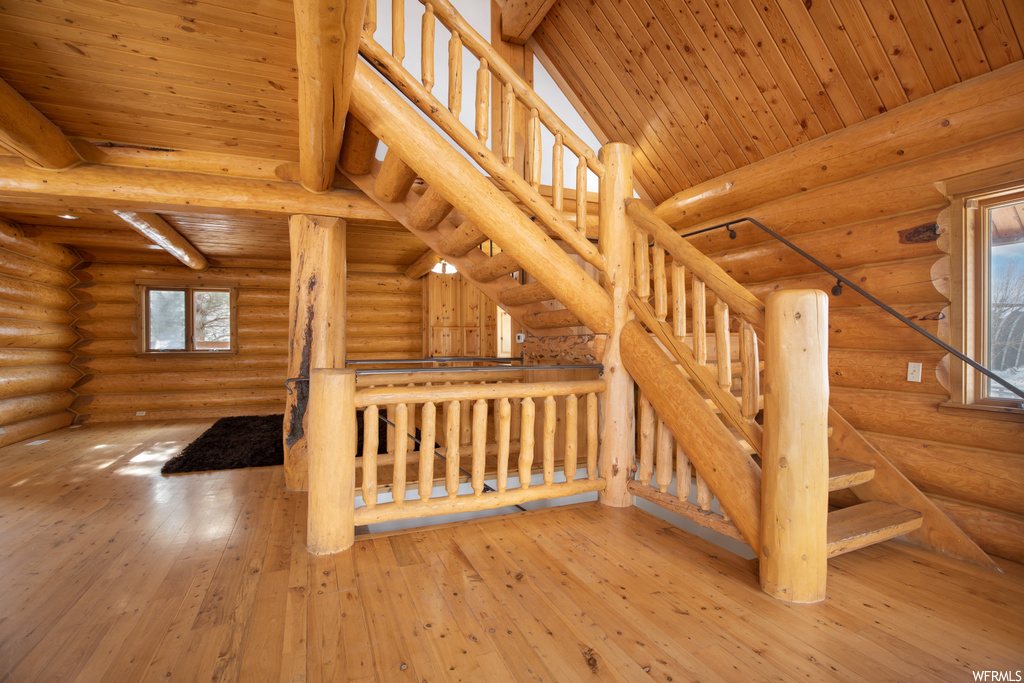 Stairway with light hardwood / wood-style flooring and log walls