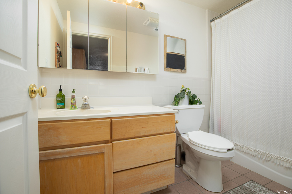 Bathroom with toilet, tile floors, backsplash, and vanity