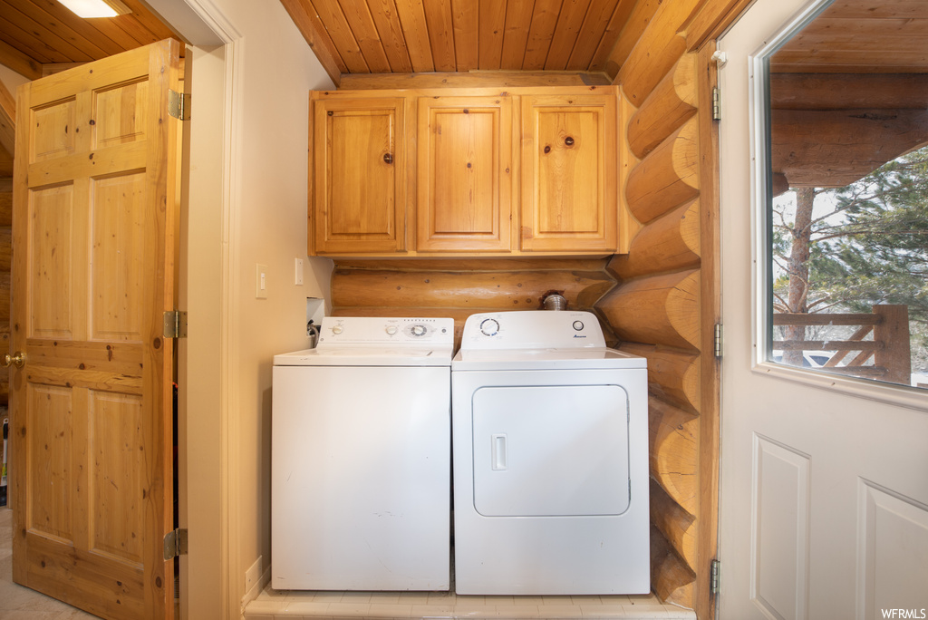 Clothes washing area with cabinets, log walls, wooden ceiling, and washing machine and dryer