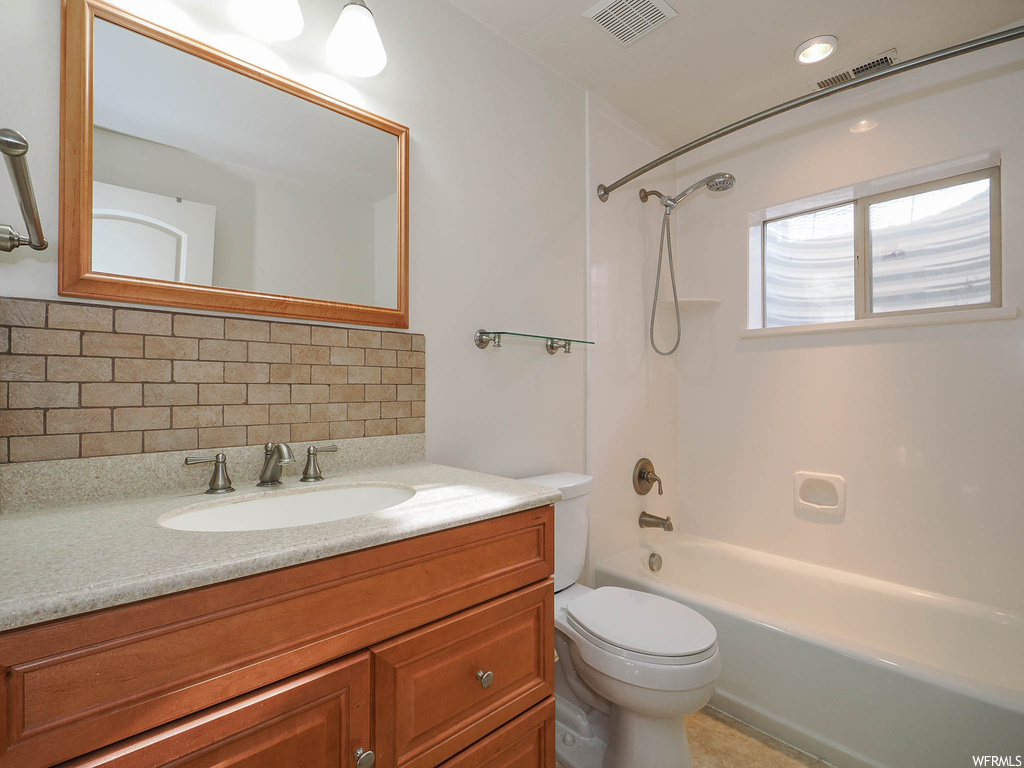 Full bathroom with vanity, bathtub / shower combination, toilet, and backsplash