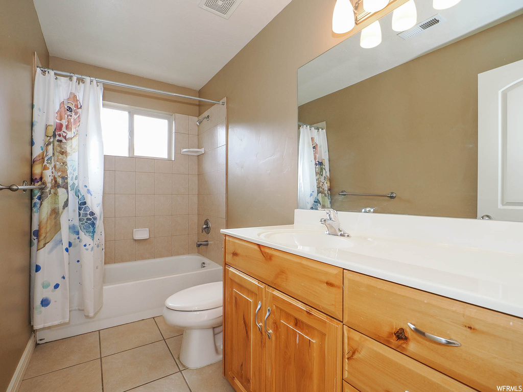 Full bathroom featuring toilet, vanity, tile floors, and shower / tub combo with curtain