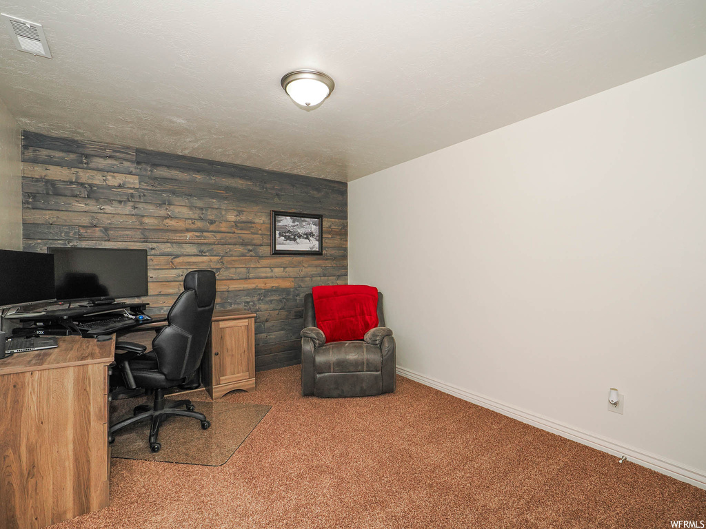 Carpeted office featuring wood walls