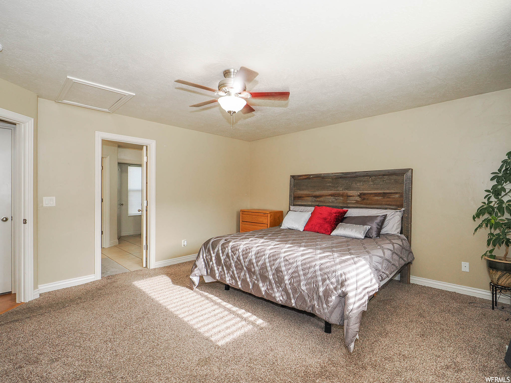 Bedroom with light carpet, ensuite bath, and ceiling fan