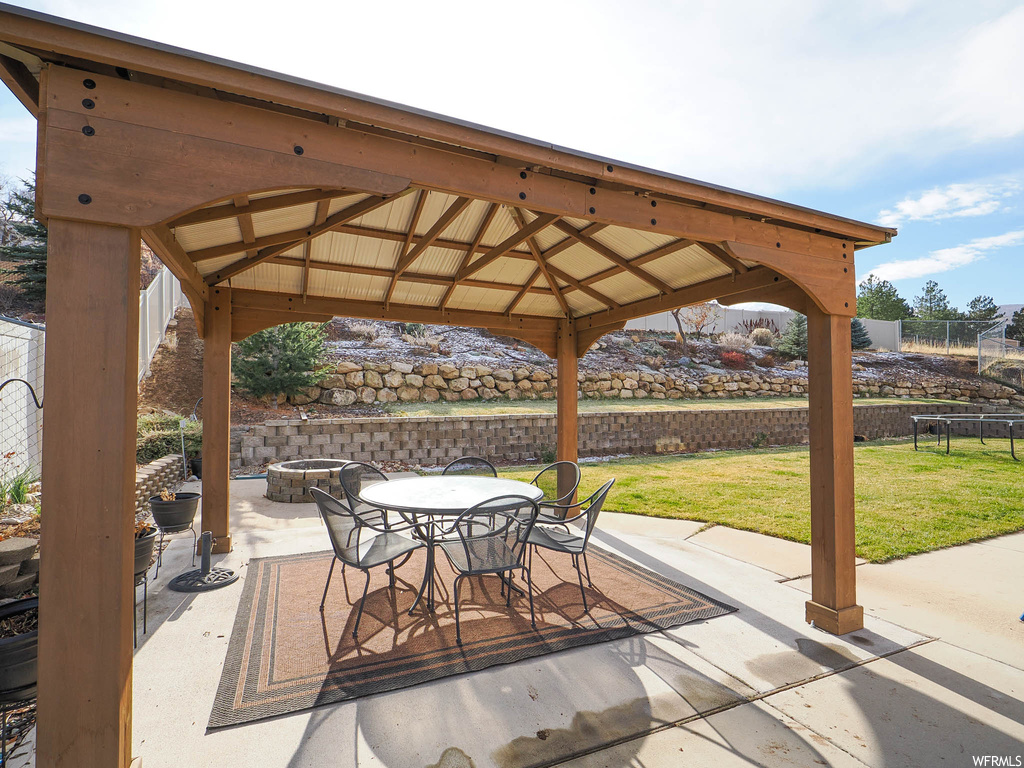 View of patio featuring a gazebo, an outdoor fire pit, and a trampoline