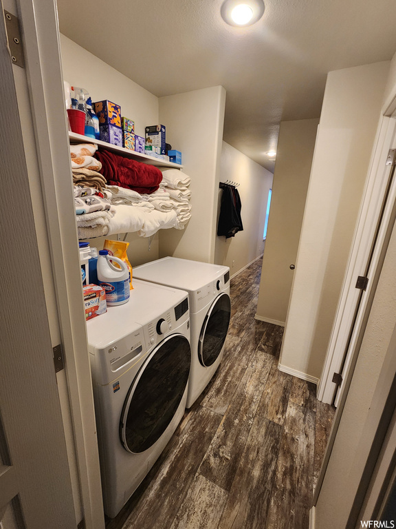 Clothes washing area with dark wood-type flooring and washing machine and dryer