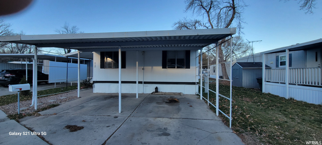 Rear view of property with a carport and a storage unit