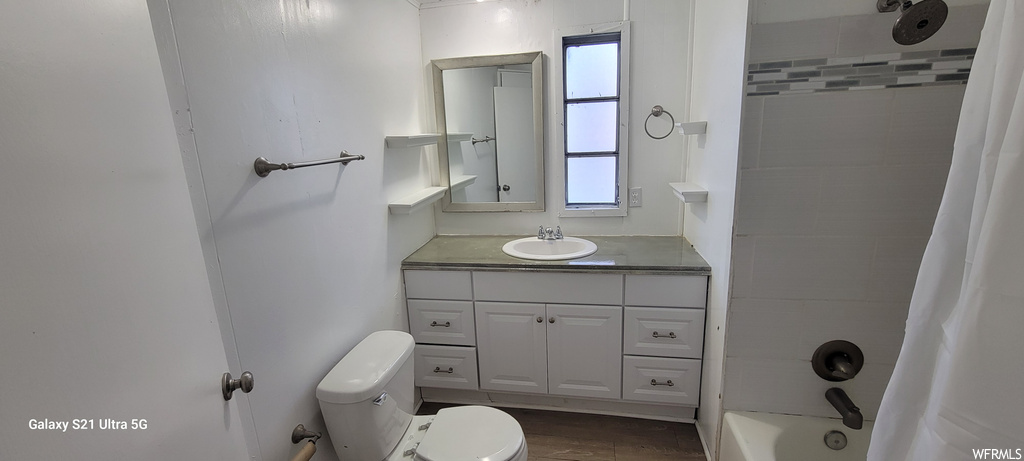 Full bathroom with oversized vanity, toilet, hardwood / wood-style floors, and shower / bathtub combination with curtain