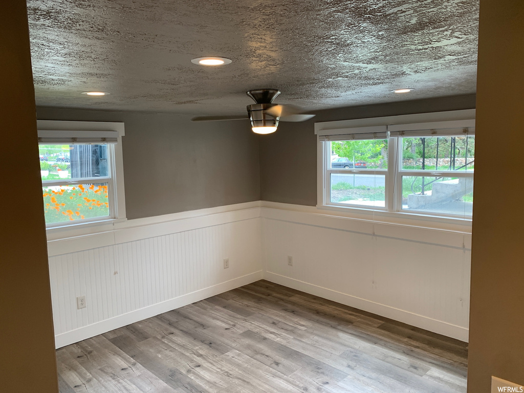 Unfurnished room with ceiling fan, a textured ceiling, and light hardwood / wood-style floors