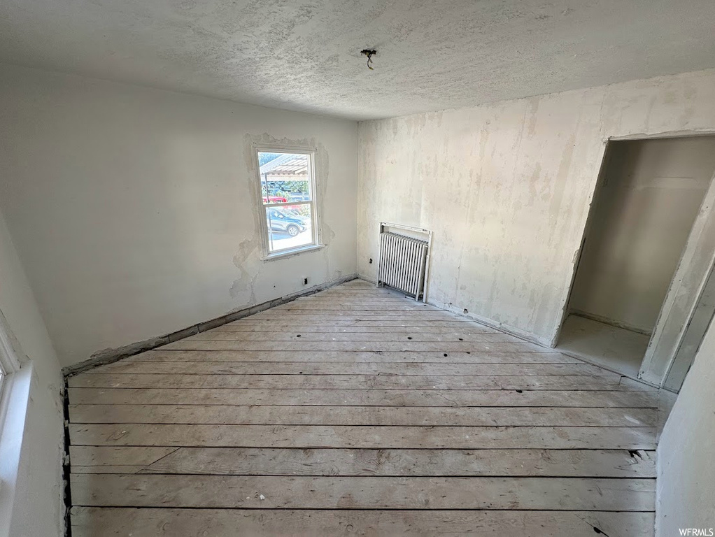 Unfurnished room featuring radiator heating unit and light hardwood / wood-style floors