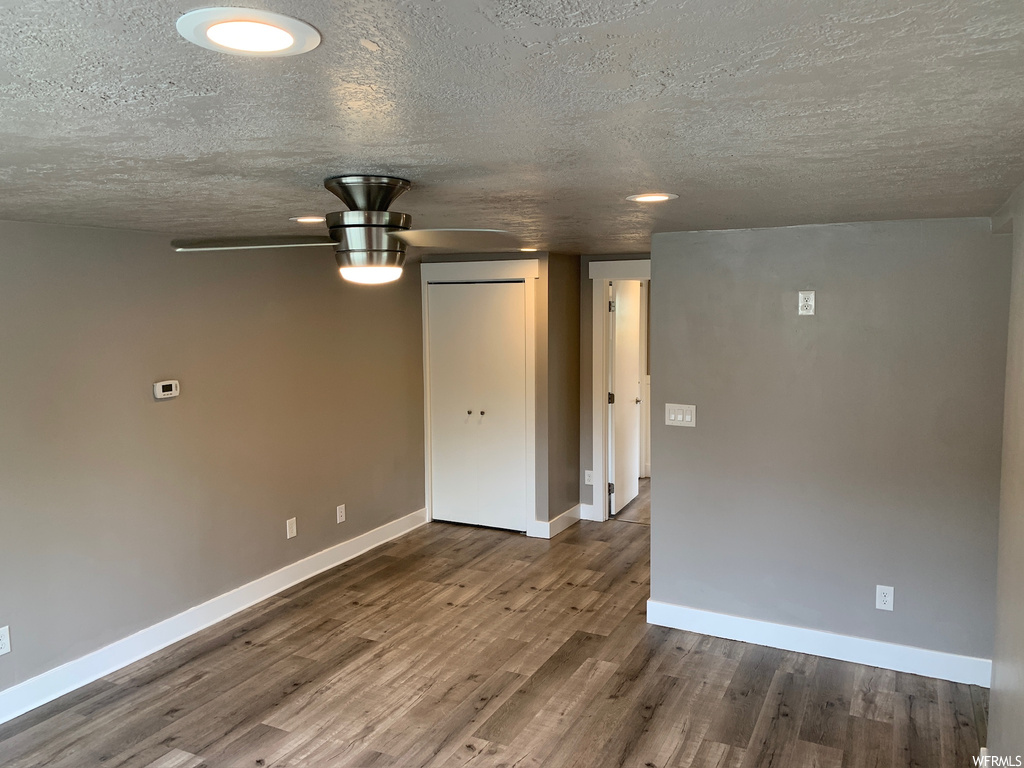 Empty room with dark hardwood / wood-style floors, ceiling fan, and a textured ceiling