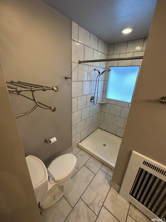 Bathroom with toilet, tile flooring, and tiled shower
