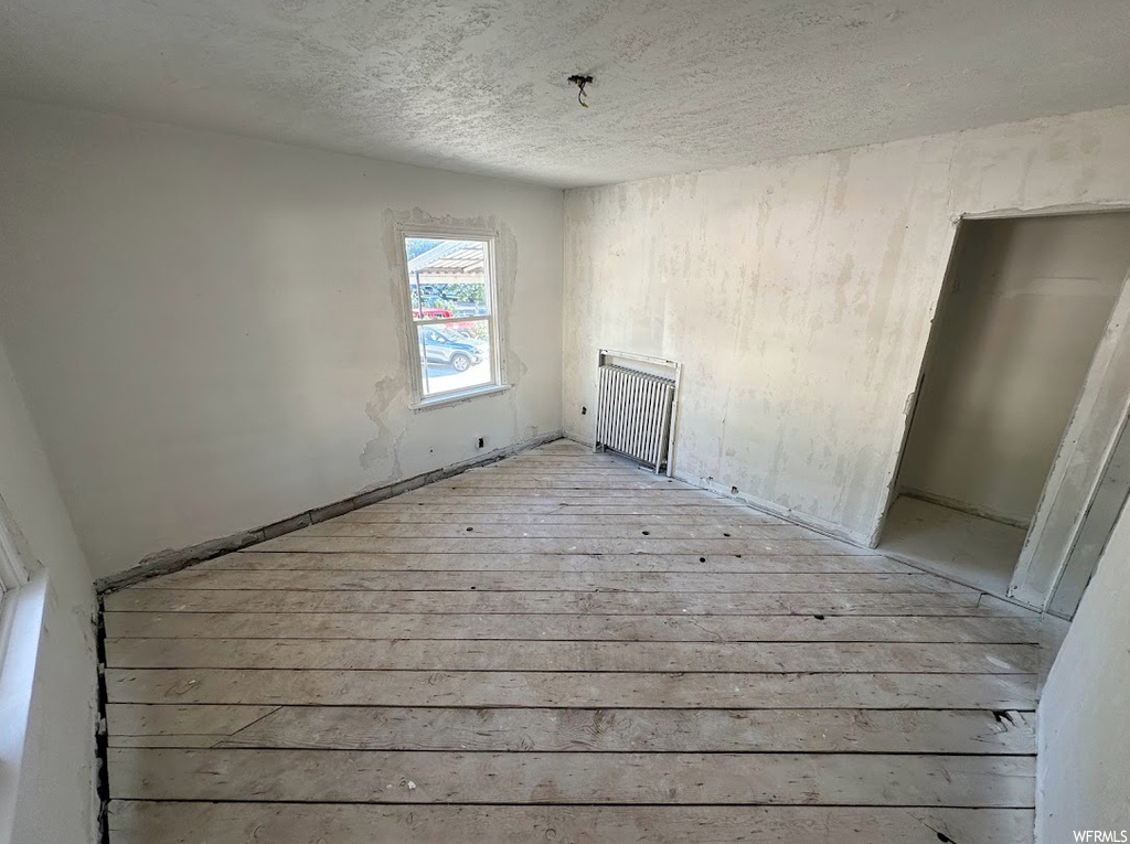 Empty room featuring radiator heating unit and light hardwood / wood-style floors