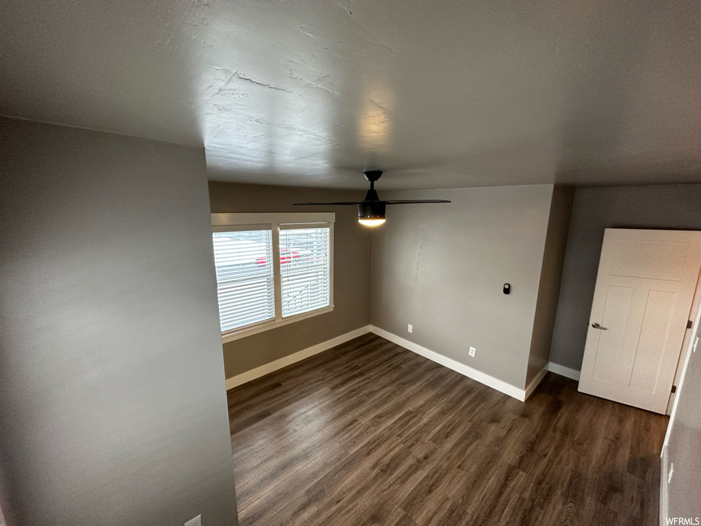 Empty room with lofted ceiling, ceiling fan, and dark hardwood / wood-style flooring