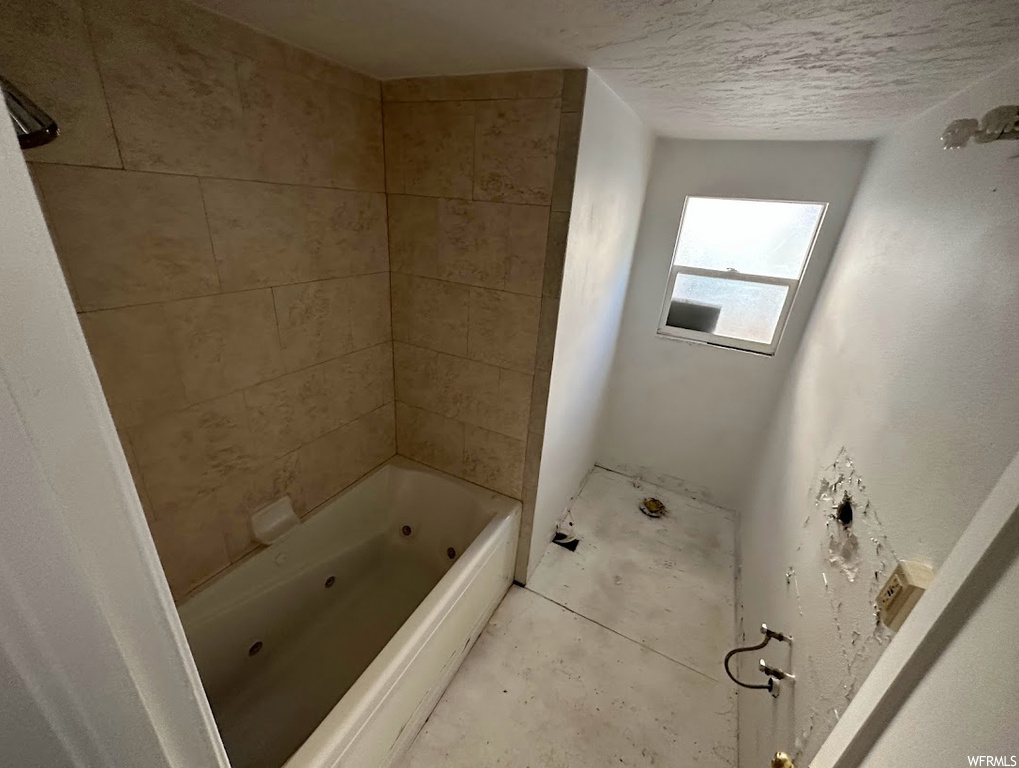 Bathroom with a textured ceiling and tiled shower / bath