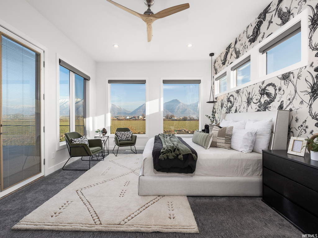 Carpeted bedroom featuring access to outside, ceiling fan, and a mountain view